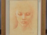 On voit le dessin du visage d'une femme dans un cadre doré