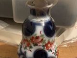 a small blue and white vase sitting on a table next to a brick