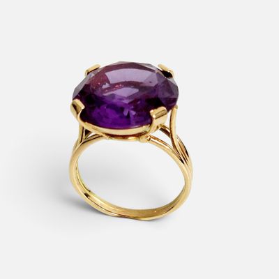 gros plan d'une bague en or avec une pierre violette