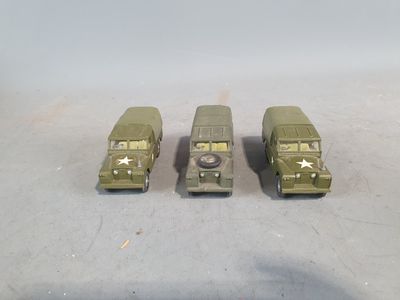 three toy army vehicles are lined up in a row on a table