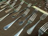 many forks and spoons laid out on a table