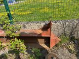 a rusted metal object on the ground next to a fence