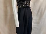 Le mannequin porte un haut noir et argenté et un pantalon noir.