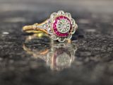 une photo d'une bague sertie de diamants et de rubis posée sur une table
