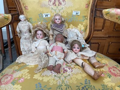 five dolls sitting on a chair in a room