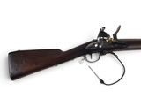 un vieux fusil exposé sur une surface blanche