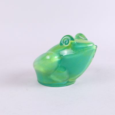 a green frog figurine sitting on a white surface