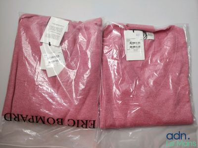 Deux t-shirts roses sont emballés dans des sacs en plastique sur une table
