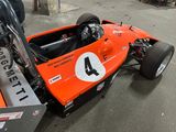 an orange race car that is parked in a garage