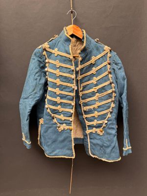 une vieille veste militaire bleue accrochée à un crochet au mur