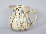a white and blue vase with a handle on a table