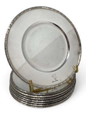 a stack of silver plates on a stand on a white surface