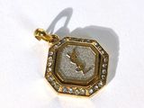 une image d'un pendentif plaqué or sur lequel figure une horloge