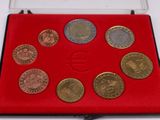 un assortiment de pièces de monnaie dans un étui rouge posé sur un fond blanc