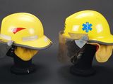 pair of yellow hard hats with face shields on display against a black background
