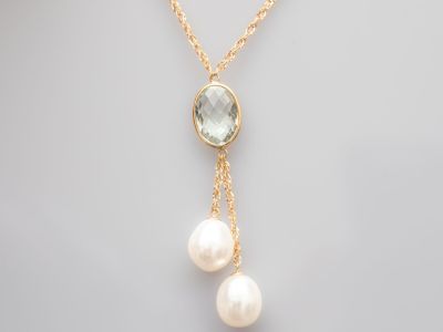 un collier en or orné de deux perles et d'une topaze bleue
