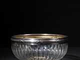 a glass bowl with a gold rim on a black surface