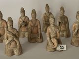 Plusieurs figurines représentant des personnages asiatiques sont exposées sur une surface blanche.