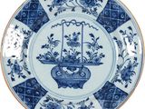 une assiette bleue et blanche sur laquelle est représenté un panier de fleurs
