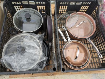 de nombreuses casseroles et poêles dans un panier posé par terre