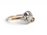 a close up of a gold ring with a diamond and blue sapphire