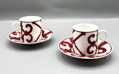 une paire de tasses à café rouges et blanches avec leurs soucoupes, posées sur une table