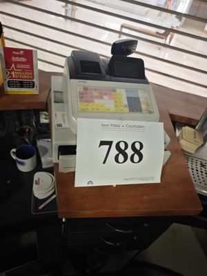une photo d'une caisse enregistreuse posée sur un bureau devant une fenêtre