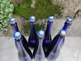 several bottles of wine are lined up on a table in front of a stone wall