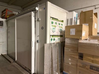 un grand réfrigérateur au milieu d'une pièce où se trouvent des cartons par terre