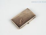 a silver cigarette case sitting on a white surface