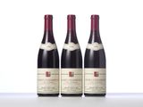 three bottles of red wine sit on a white surface