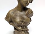 a bronze bust of a woman with a flower in her hand