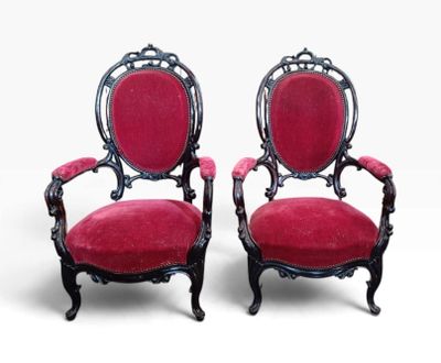 une paire de fauteuils en velours rouge aux accoudoirs sculptés
