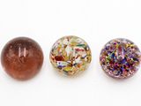 trois perles de verre de couleurs différentes posées les unes à côté des autres sur une surface blanche