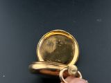 a person holding a gold pocket watch in their hand