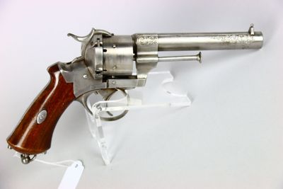 un vieux revolver avec une poignée en bois sur une surface blanche