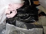 a pile of clothes and bags on a bed