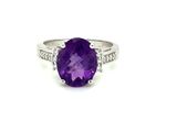 a close up of a ring with a purple stone and diamonds