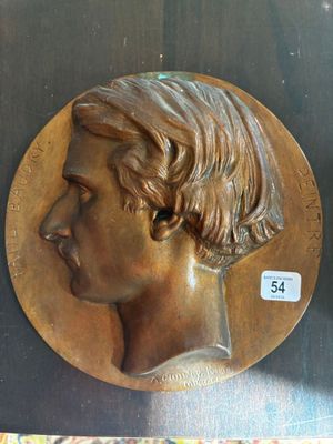 une plaque en bronze représentant un homme avec une coupe de cheveux