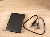 une batterie externe noire et un chargeur posés sur une table en bois