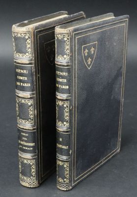 two old books are sitting side by side on a black surface