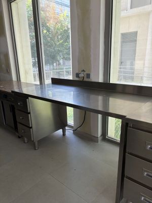 une grande table de travail en acier inoxydable au milieu d'une pièce