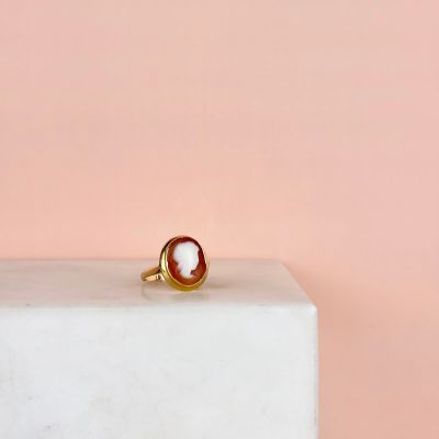 un gros plan d'une bague en or ornée d'un coquillage, posée sur un bloc de marbre