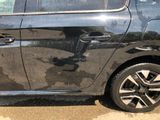 a black car that has been damaged and is parked on the side of the road
