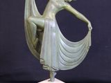 a bronze statue of a woman holding a scarf on top of a marble base