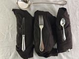 a spoon, fork, and spoon rest on a napkin
