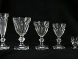 quatre verres à pied et un verre à vin sur fond noir