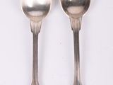 pair of silver spoons on a white surface with a white background