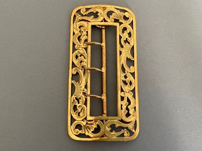 an image of a gold buckle on a gray surface