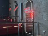 tables and booths in a restaurant with a neon sign on the wall